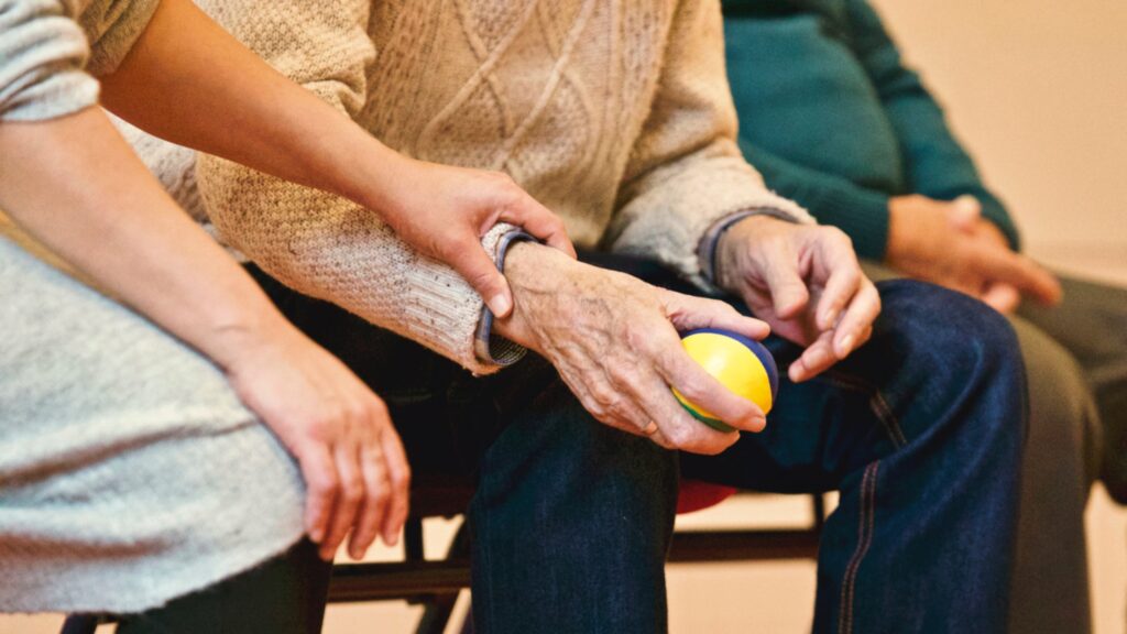 Eine Pflegekraft hält die Hand eines älteren Menschen